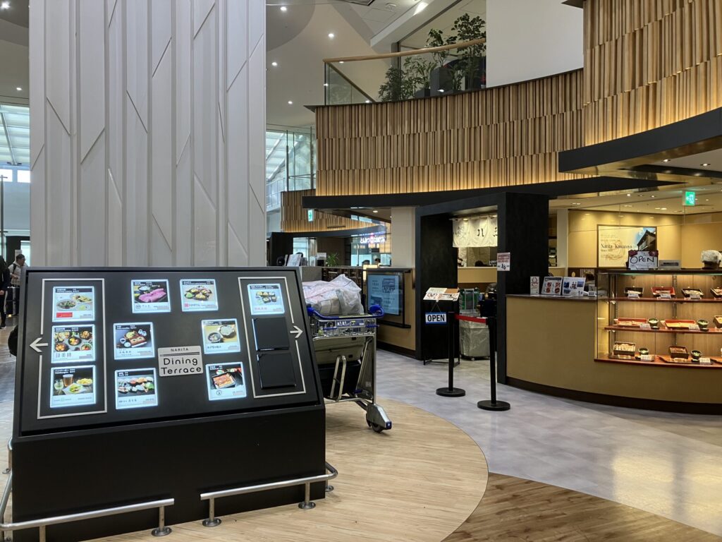 成田空港第1ターミナル4階Dining Terraceの店舗案内モニターと飲食店エリア。