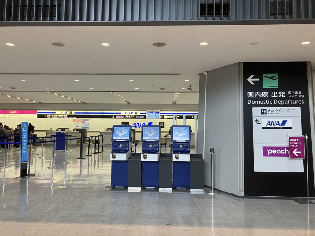 成田空港第1ターミナル1階の国内線出発エリア。ANAとPeachのチェックインカウンターとセルフチェックイン機が並んでいる。