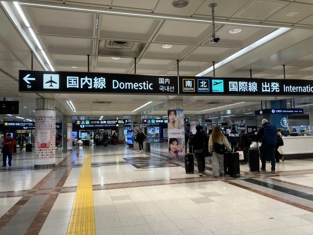 成田空港第1ターミナルの地下エリアから、国内線・国際線への案内表示が並ぶ通路。