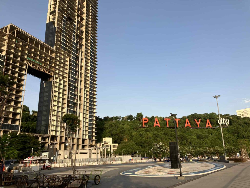 パタヤの象徴的な“PATTAYA CITY”サインと、その横にある未完成の高層ビルの朝の風景
