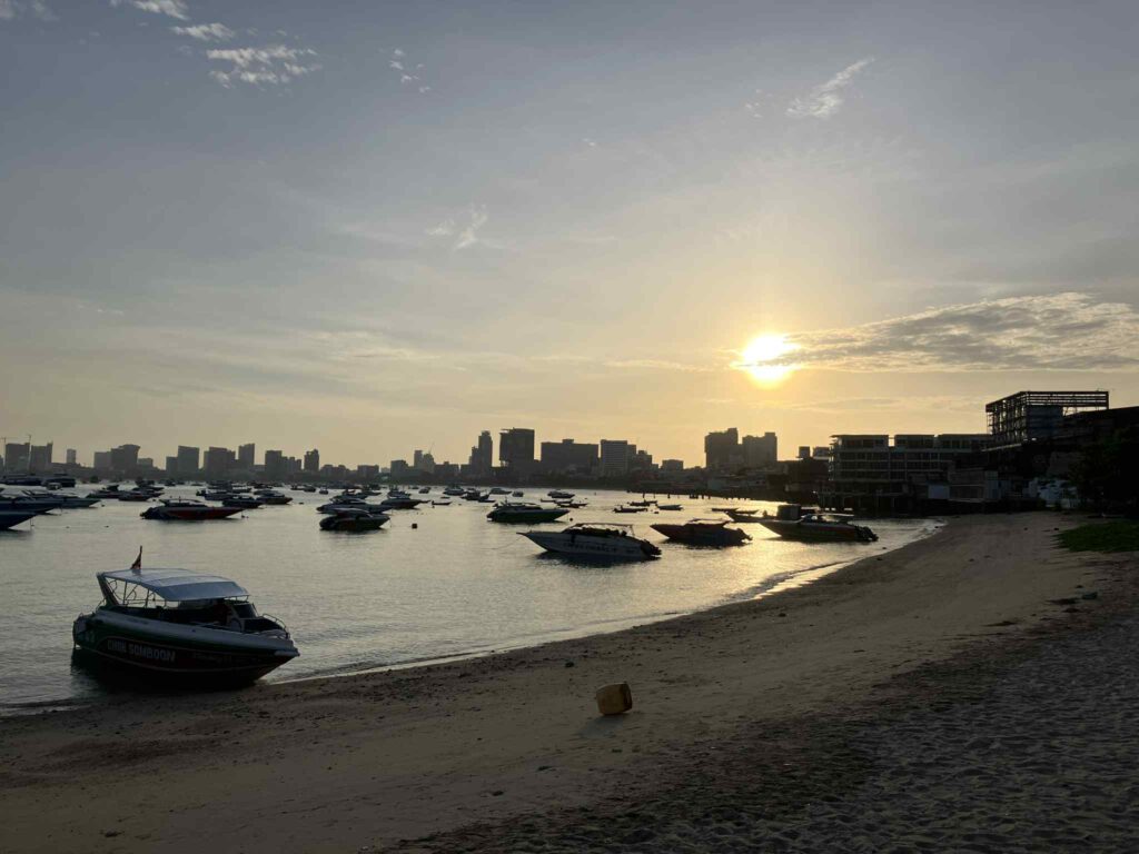 朝日が差し込むパタヤ湾と停泊するボート群、バリハイ桟橋近くの静かな浜辺の風景