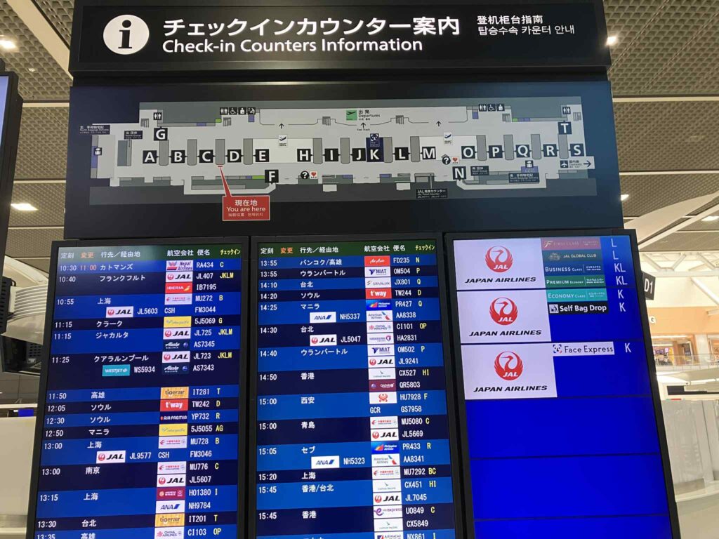 成田空港第2ターミナルのチェックインカウンター案内板と発着情報表示。航空会社とカウンター位置が一覧できる。