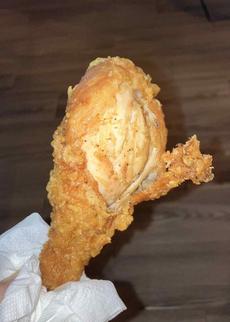 パタヤ フライドチキン ドラムスティックを手に持って食べる