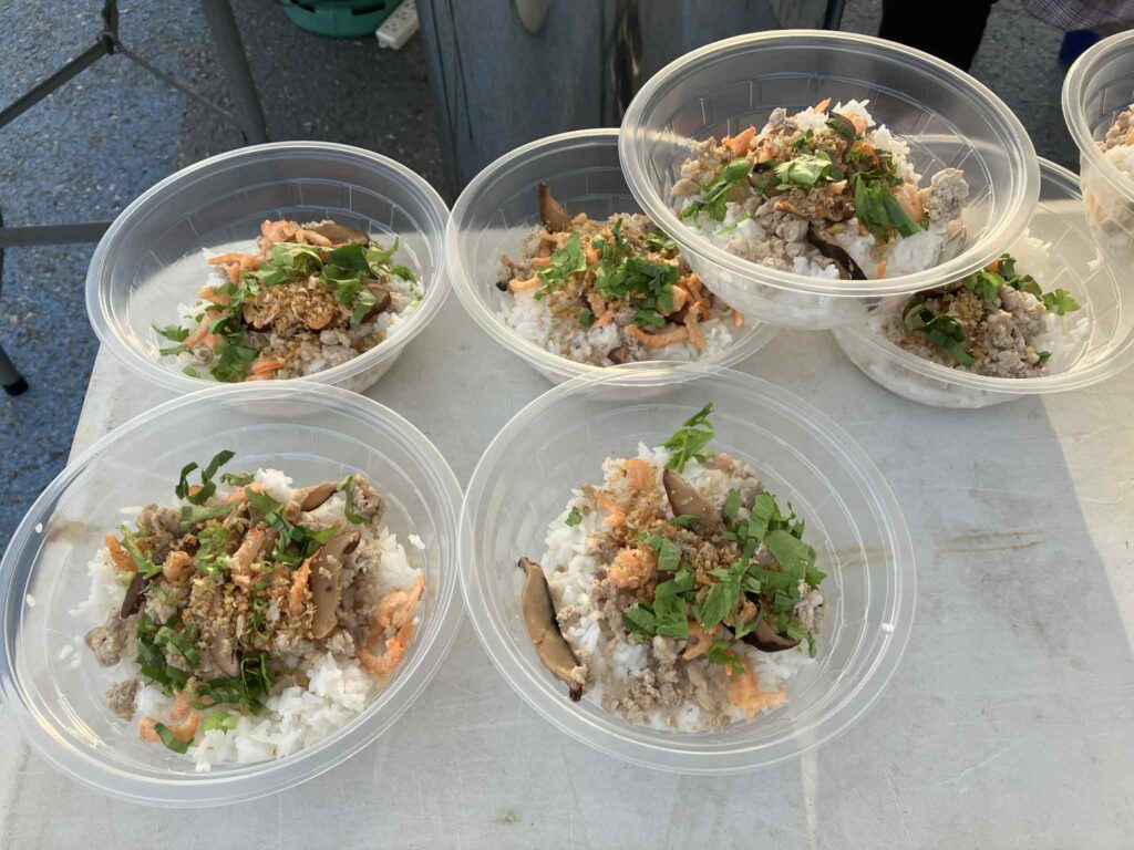パタヤトレイル2025のゴール地点で提供された朝食メニュー、カオトムヘーン（汁なしおかゆ）の配膳風景。