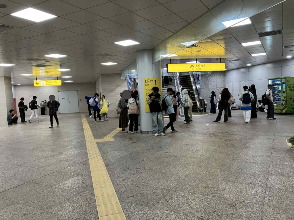 雨の中、駅構内で雨宿りする人々