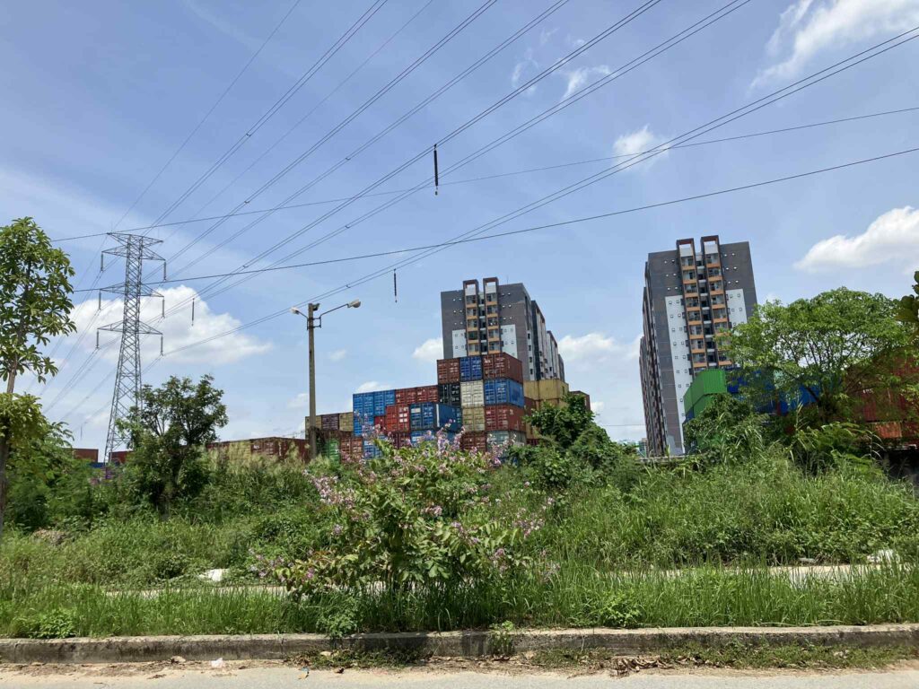 コンテナ群と住宅地が隣り合う風景。