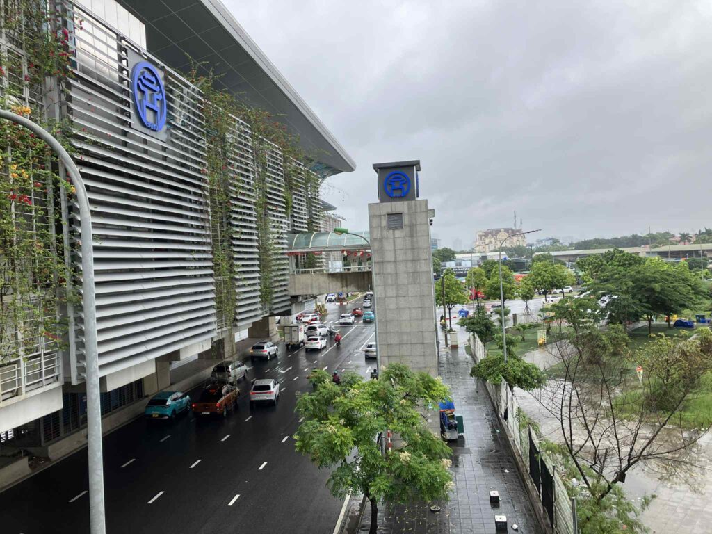 雨の日のNhon駅（Ga Nhổn）外観。高架駅と駅前道路の様子が見える