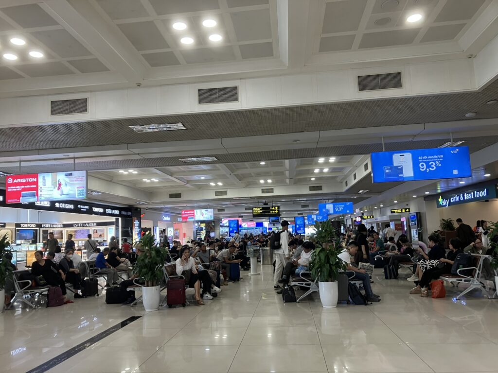 ノイバイ空港T1の待合いエリア奥側の様子。Sky Cafe fast foodや複数の売店があり、出発前の時間を過ごす乗客で賑わう。