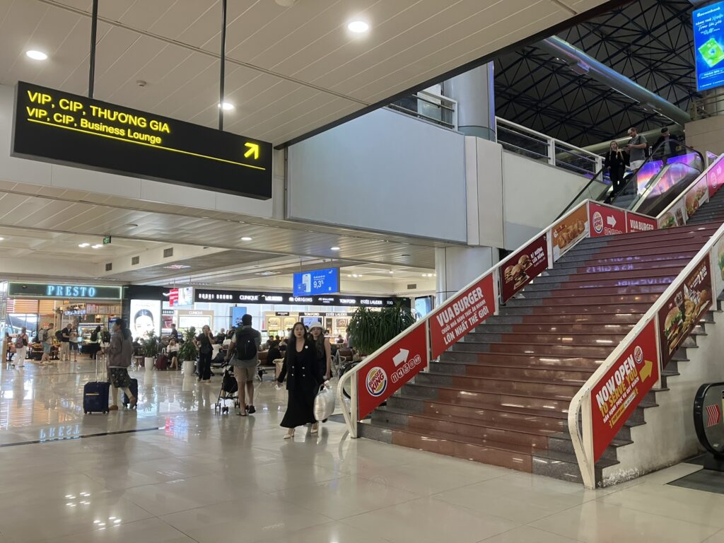 ノイバイ空港T1でVIP・CIPラウンジへ向かう通路。上部にラウンジ案内サインが掲示され、エスカレーター横の分かりやすい位置にある。