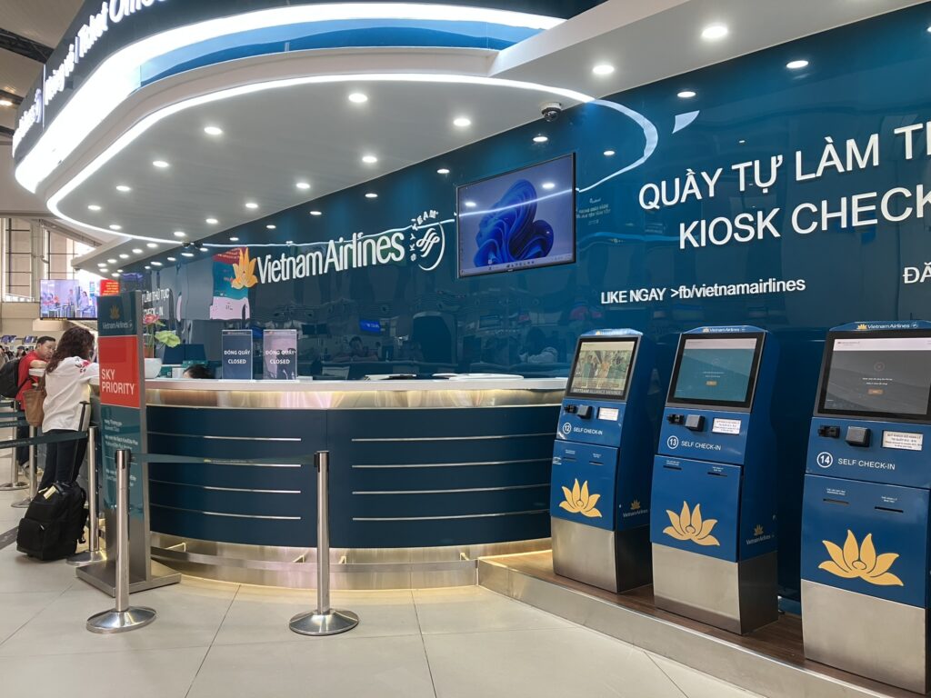 ノイバイ空港T1出発階にあるVietnam Airlinesサービスカウンターとキオスク。青を基調としたブランドカラーで統一され、案内スタッフが常駐している。