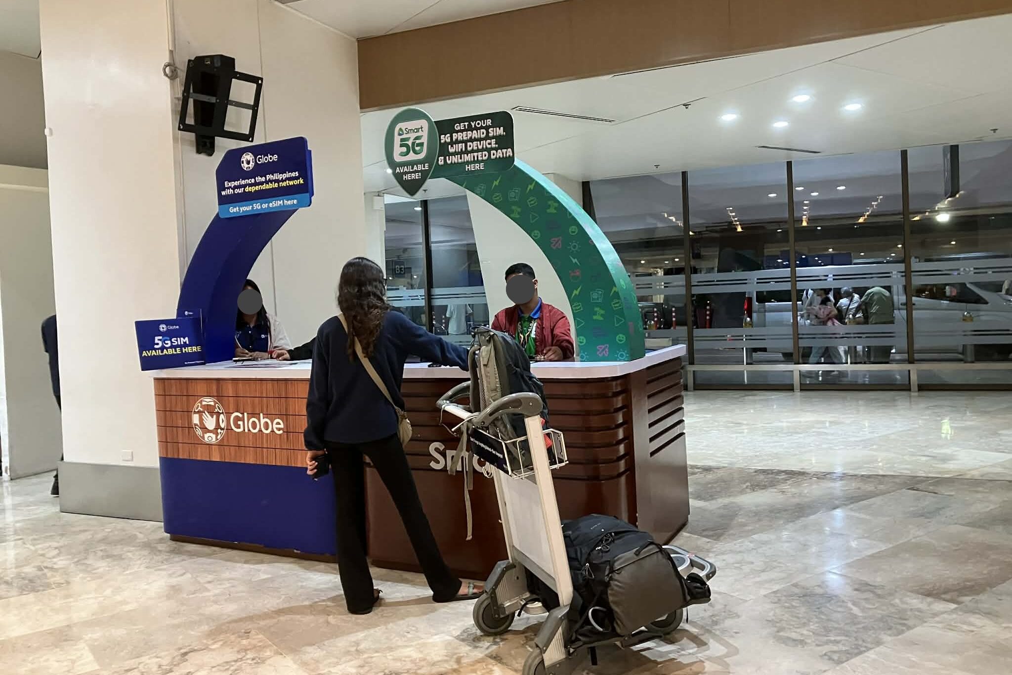 マニラ空港NAIA到着フロアのSIM販売ブースで対応するGlobeとSmartのカウンター