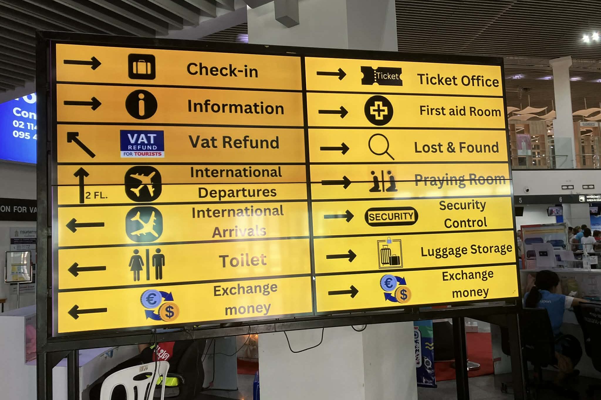 ウタパオ空港の施設案内サイン（チェックイン・到着・両替など）