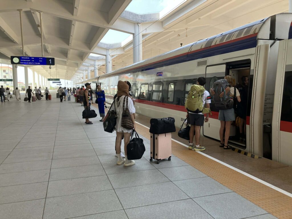 ビエンチャン駅のホームに停車するラオス中国鉄道の列車と乗車する旅行者