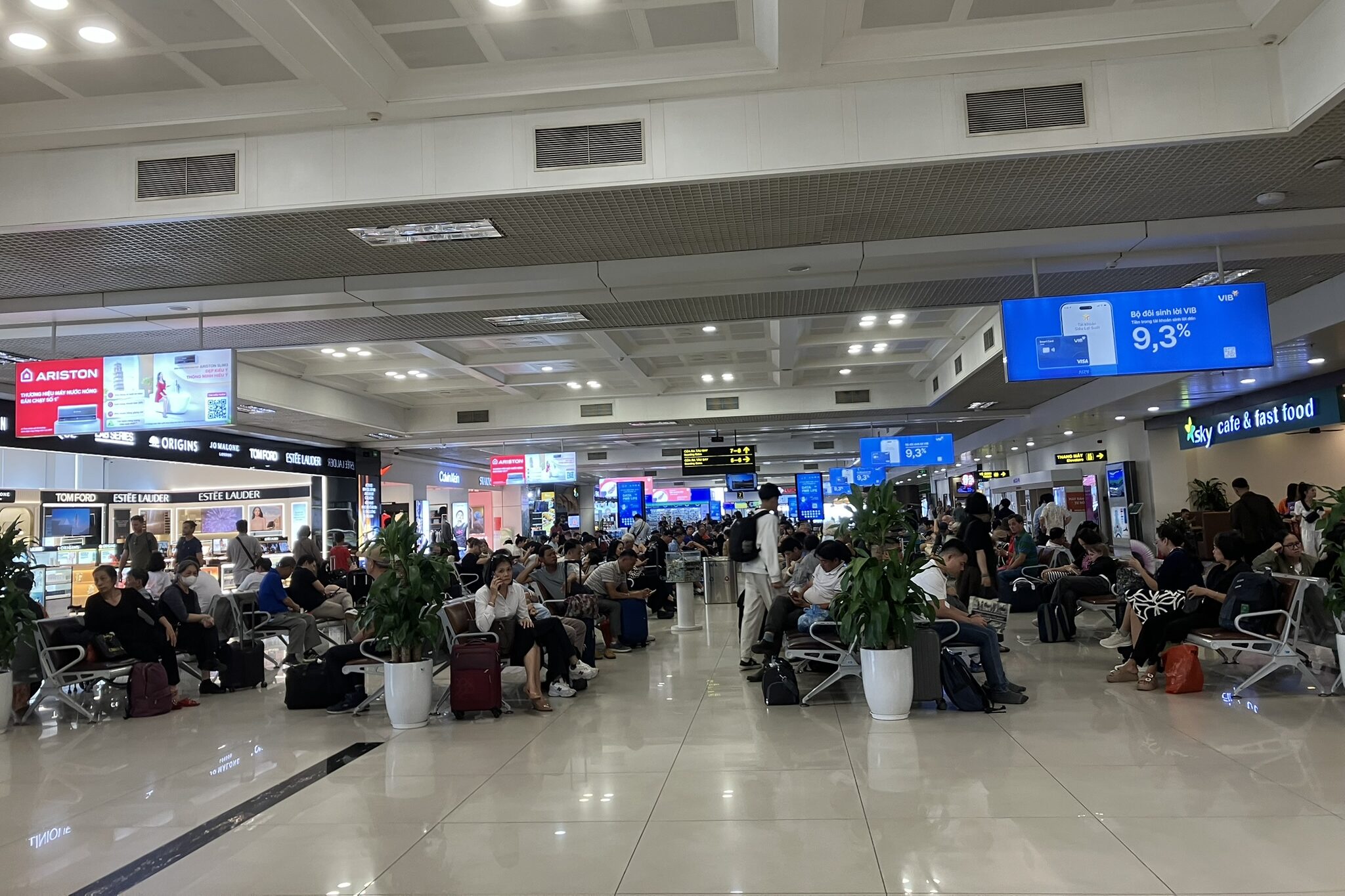 ノイバイ空港T1の待合いエリア奥側の様子。Sky Cafe fast foodや複数の売店があり、出発前の時間を過ごす乗客で賑わう。