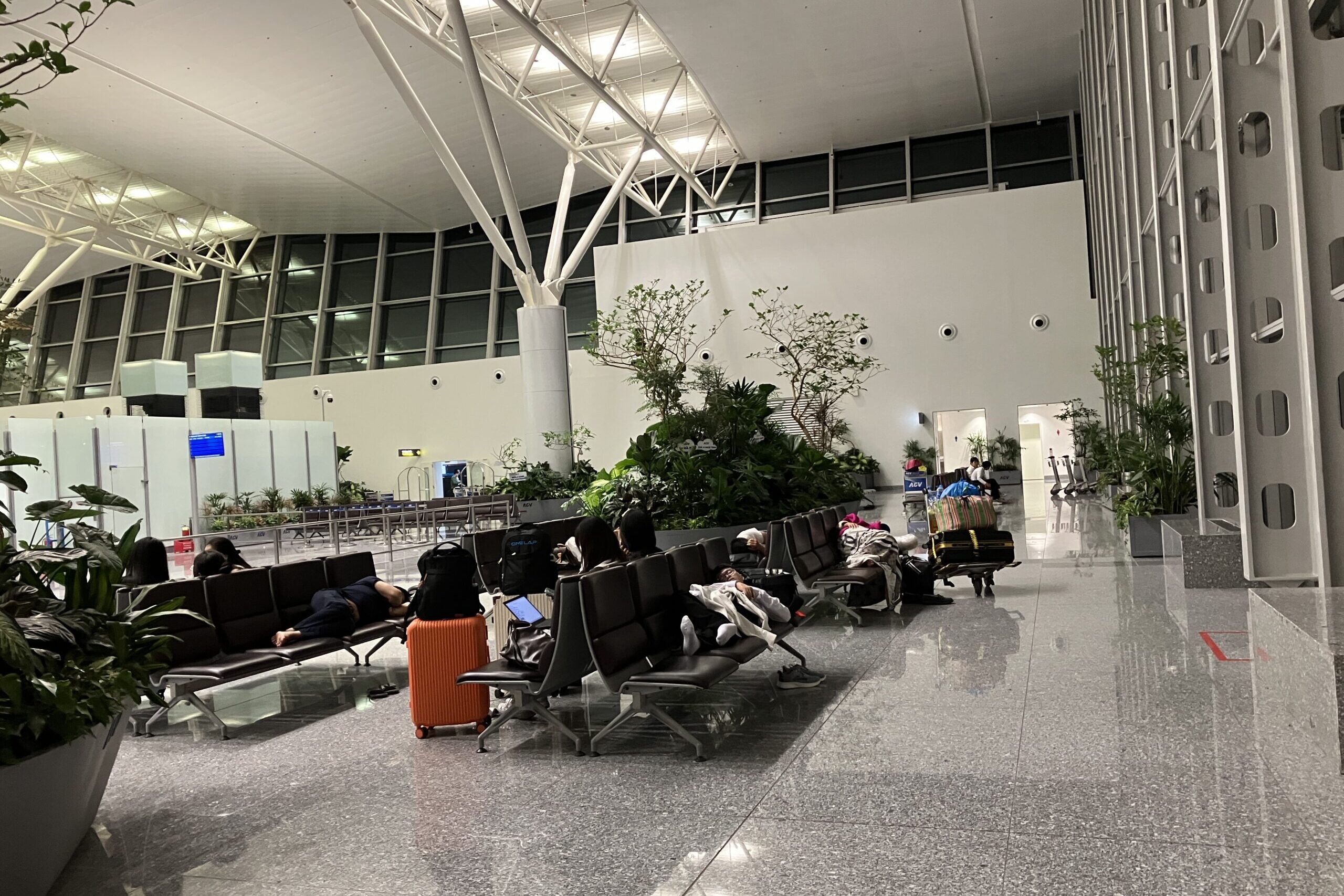 ノイバイ空港T2の3階出発フロアで休む旅行者