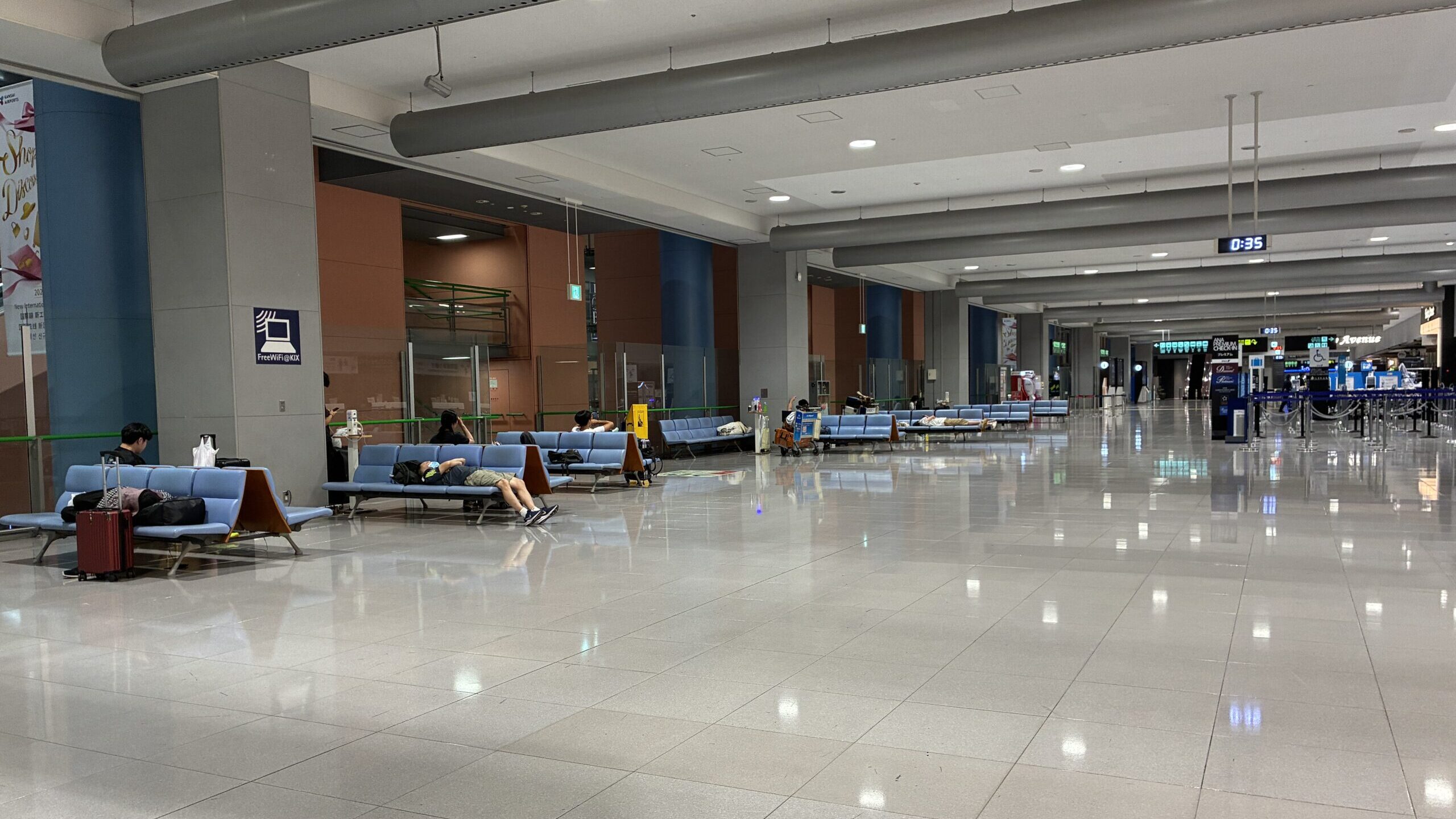 関西空港第1ターミナル2階のベンチで休む旅行者